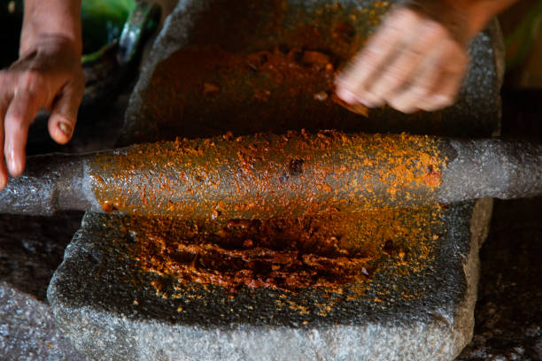 Woman from an indigenous community in Oaxaca preparing traditional red mole with a metate, a tool for grinding ingredients in Mexico..