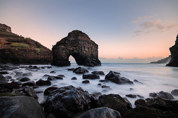 Dramatic coastal scene featuring a natural rock arch surrounded by ocean waves and rugged cliffs at sunset, Tenerife, Canary islands. Tranquil and scenic. Beautiful landscape perfect for travel and tourism concept.