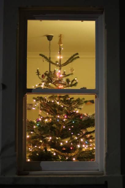 istock Christmas tree at night through a house window, covered in lights and decorations 2191674285