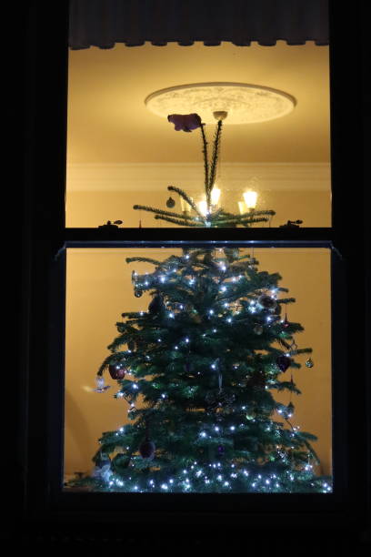 istock Christmas tree at night through a house window, covered in lights and decorations 2191674561