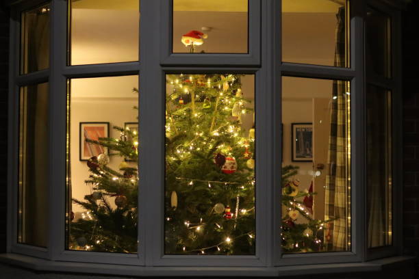 istock Christmas tree at night through a house window, covered in lights and decorations 2191674596
