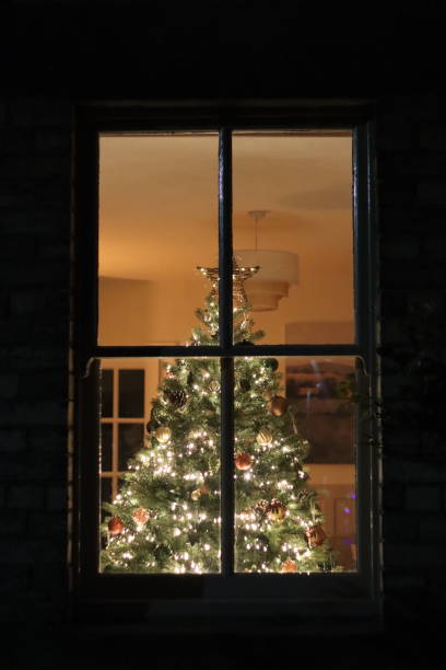 istock Christmas tree at night through a house window, covered in lights and decorations 2191675799