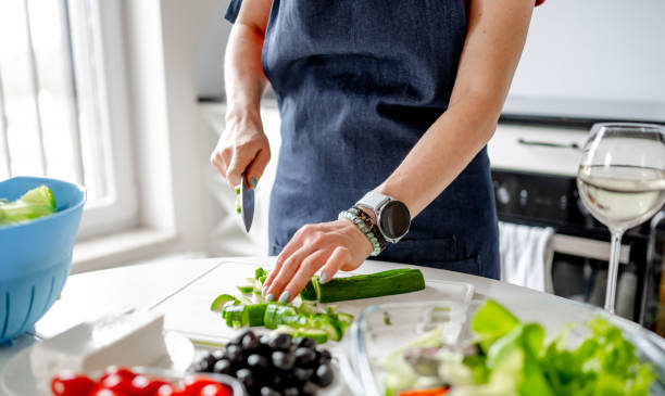istock Woman At Home In Kitchen Cutting Cucumbers 2191678572
