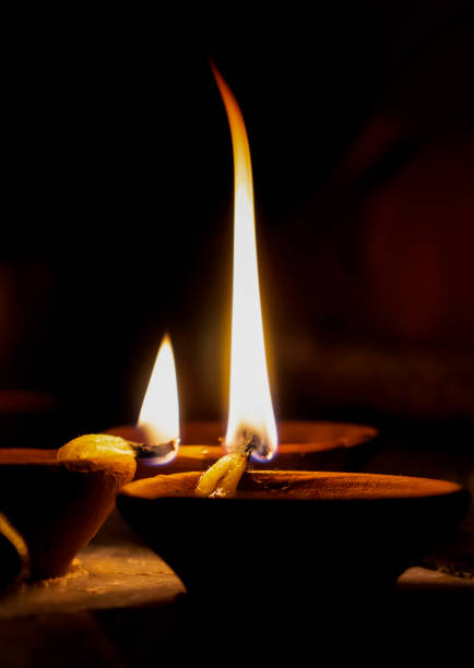Lighten diwali diya with long flame with another diya (lamp).