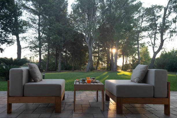 istock Two chairs and a table are on a patio, surrounded by trees 2191683733