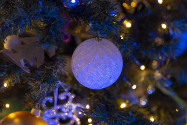An elegant ornament hangs on a beautifully decorated Christmas tree with lovely blue lights