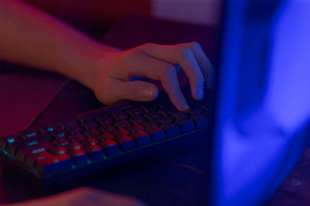 istock Hands Typing on Backlit Keyboard with Monitor in Dark Background 2191685906