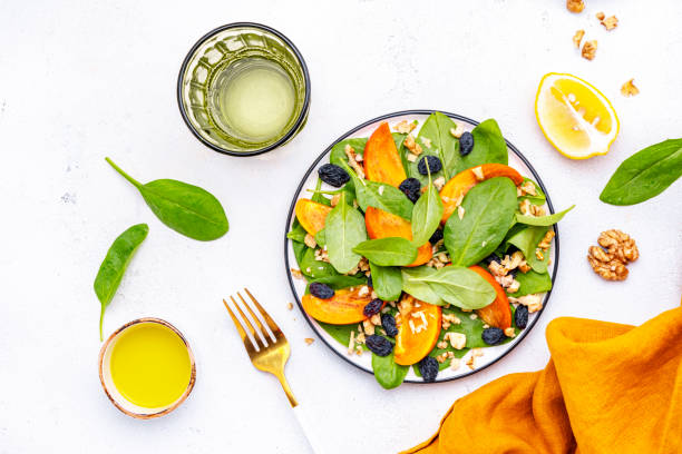 istock Wintervegan persimmon salad with walnuts, blue raisin and spinach, white background, top view 2191689950
