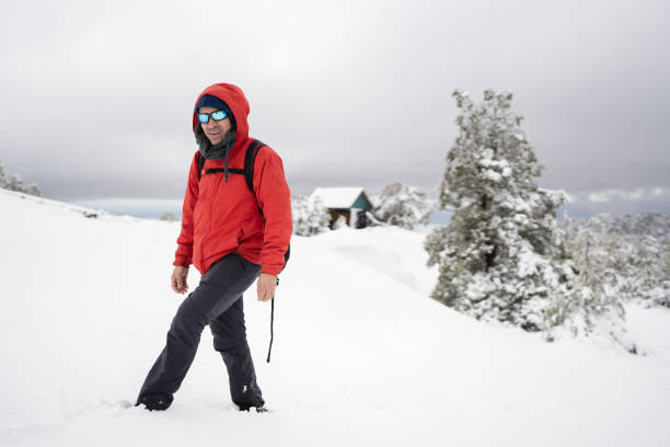 Male hiker walking on snowy mountain path in winter, enjoying the peace and tranquility of nature
