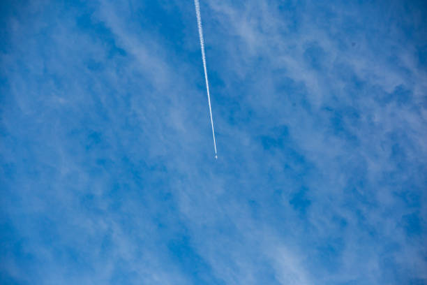 A plane leaving a white trail in a blue sky.