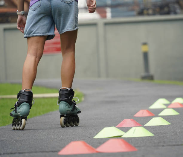 A vivid image depicting a series of pink and blue cones arranged on a grey paved surface, highlighting an outdoor roller skating training activity focused on enhancing agility and balance.