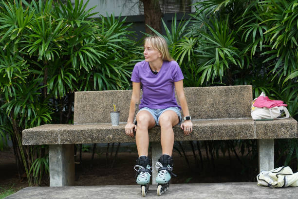 A teenage boy with Down syndrome and his mom sit on their skateboards at a park in Central Oregon, enjoying a drink of water after a fun afternoon session of skateboarding.