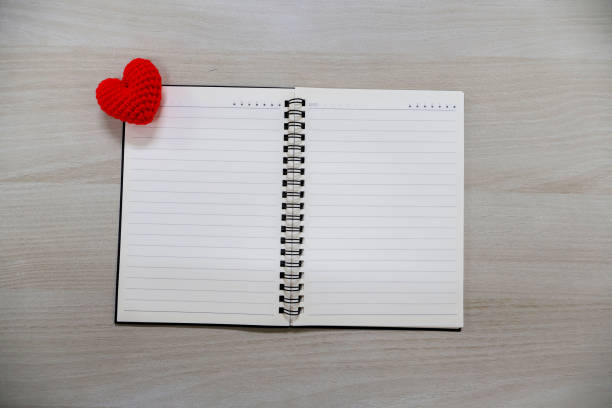 Notebook with lines and hearts on wooden table background. Valentine Day Theme