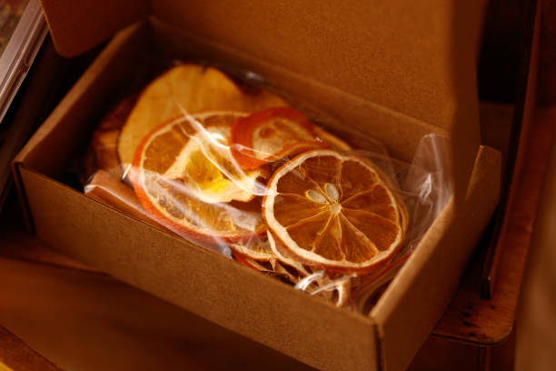 A box of dried fruit, including oranges and apples, sits on a table. The fruit is in a plastic bag and he is a mix of dried fruit