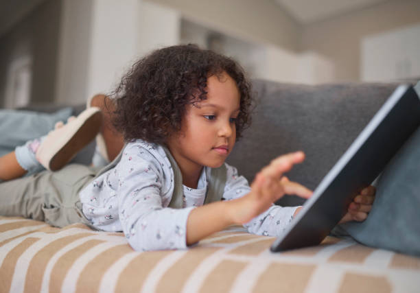 istock Engrossed Child with Tablet on Striped Couch 2191718177