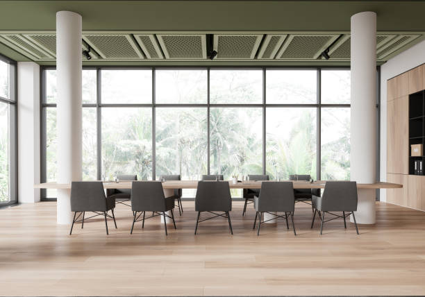 istock Modern conference room interior with large table and chairs in a bright, spacious setting with floor-to-ceiling windows and natural wood flooring. 3D Rendering 2191723770