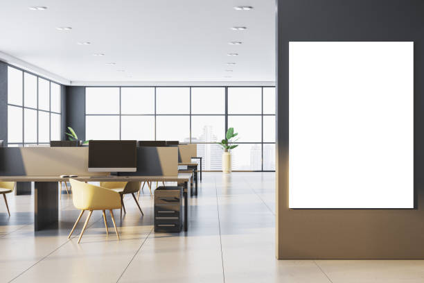 istock Modern office interior with partitioned desks, chairs, and large window view. Vertical blank poster on wall. Bright daylight setting. 3D Rendering 2191725872