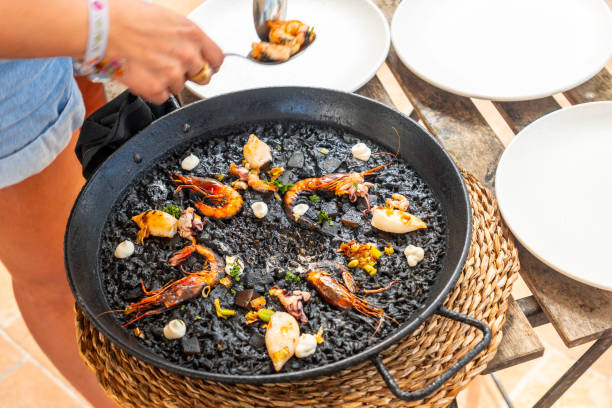 istock Chef serving fresh black rice paella with seafood in mallorca 2191726085