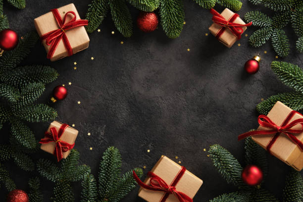 istock Christmas frame with gift boxes with red ribbons and pine branches on dark background. Place for your text. 2191730583