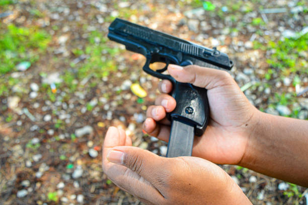 A man hand holds a gun and is preparing bullets for reloading. Concept of man terrorist, killer, armed forces,Theft, criminals, Crime of violence. focus on gun, noisy, exposure, similar others