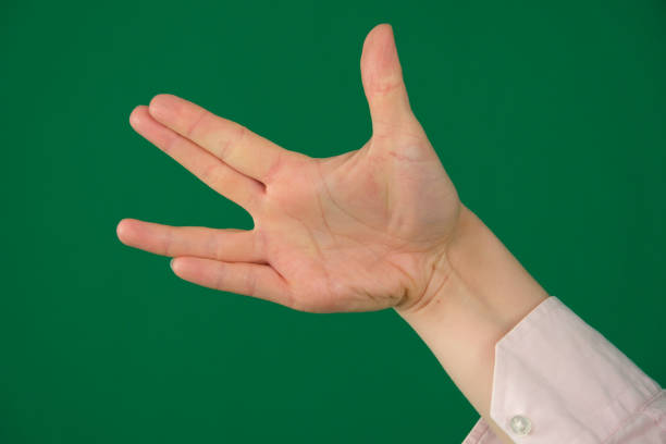 Vulcan greeting, womans hand, isolated on green. High quality photo
