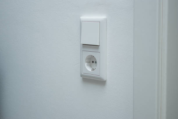 istock Close up of a double electric light switch and a socket on white empty wall 2191736041