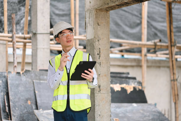 istock A construction engineer in safety gear uses a tablet at a construction site. He inspects the site, surrounded by scaffolding and building materials, and makes notes 2191741069