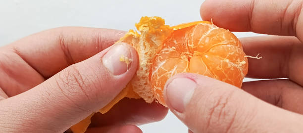 istock A boy's hands peeling tangerines. A man peeling  mandarin close-up. 2191741434