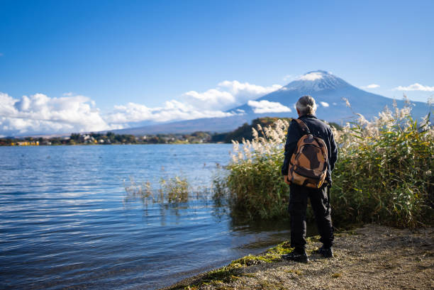Rear View Of old Man discovering beautiful Mt. Fuji By Lake Against Mt Fuji In springtime