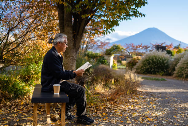 senior adult enjoy relax reading book in garden public park in the light of morning charm, feel comfortable mind reading story book in morning light in holidays weekend with snowless fuji mountain on the background