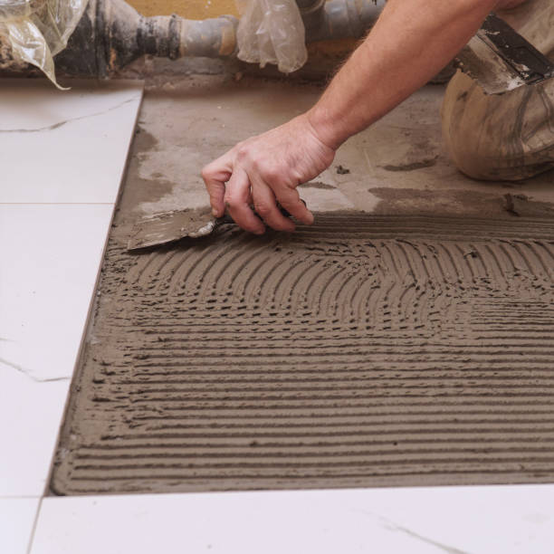 istock Construction worker applies cement for laying floor ceramic tiles with spatula 2191744141