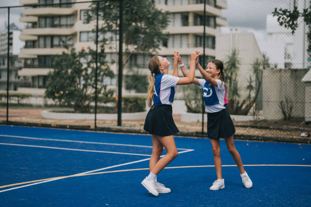 istock 2 Australian netball team players high five after scoring 2191746523