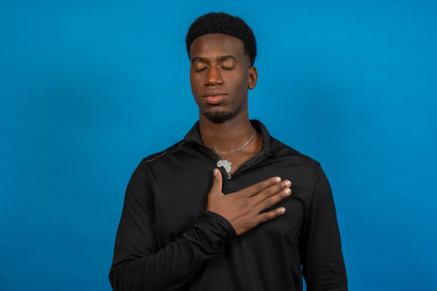 istock Young man pledging allegiance with hand on chest and closed eyes 2191750929