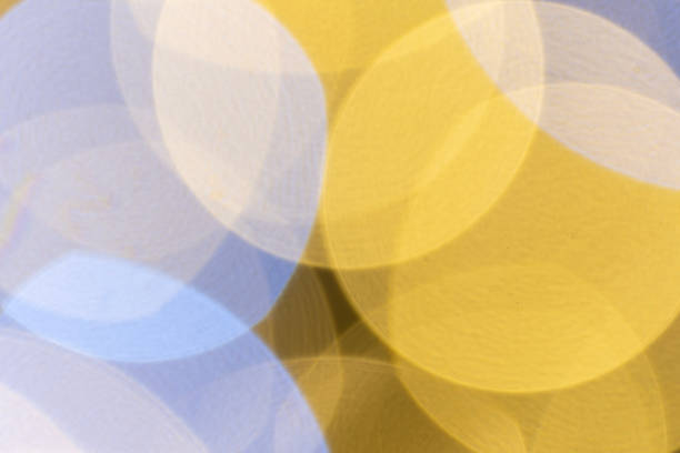 A creative abstract bokeh effect with overlapping circles of warm yellow and cool blue light, creating a harmonious and visually pleasing pattern. The soft focus and gradient lighting give the image a calming and dreamy atmosphere, perfect for use in design projects, backgrounds, or artistic compositions. Ideal for digital art, posters, invitations, or seasonal greetings with a modern aesthetic