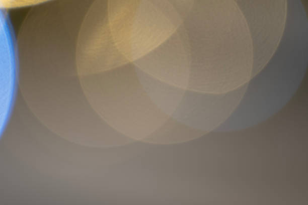 A creative abstract bokeh effect with overlapping circles of warm yellow and cool blue light, creating a harmonious and visually pleasing pattern. The soft focus and gradient lighting give the image a calming and dreamy atmosphere, perfect for use in design projects, backgrounds, or artistic compositions. Ideal for digital art, posters, invitations, or seasonal greetings with a modern aesthetic