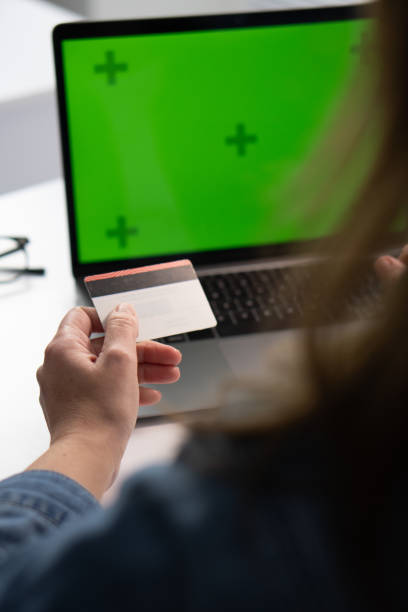istock A person confidently holds a credit card before a laptop with a bright green screen, preparing for online transactions, highlighting modern consumer habits and technological advancements in shopping 2191754324