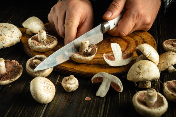 istock Hands expertly cut mushrooms on a rustic wood board, showcasing their fresh, earthy textures. The kitchen is alive with the anticipation of a delicious meal to come 2191755229