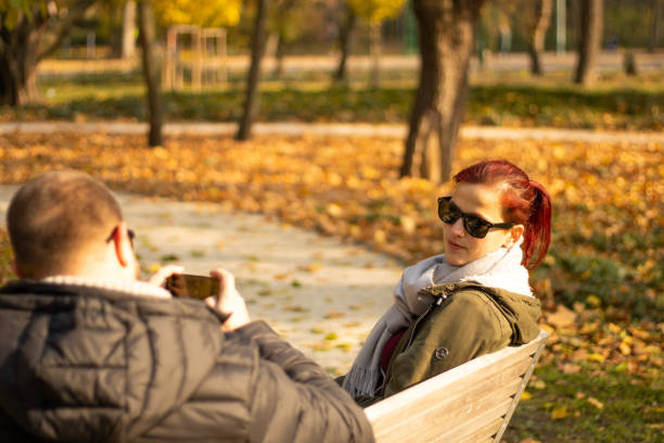 istock couple sitting on park bench in autumn 2191758660