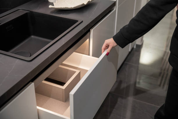 istock A woman opens a drawer in a contemporary kitchen, revealing organized compartments 2191761921