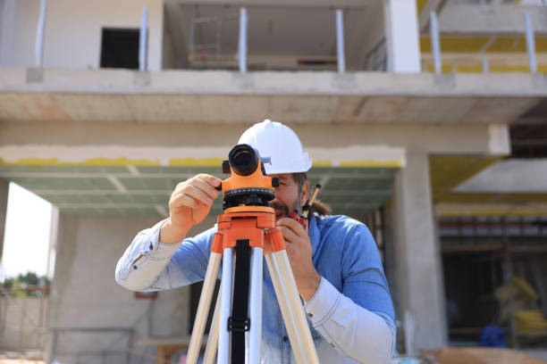 istock Surveyor with walkie-talkie looking through measuring level on construction site 2191768538