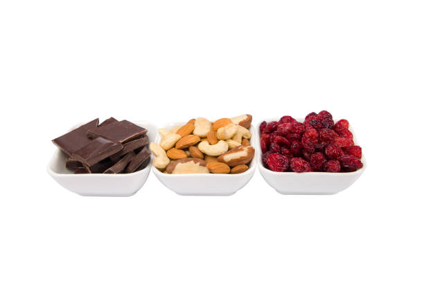 Chocolate, raspberry and nuts in white bowls over white background
