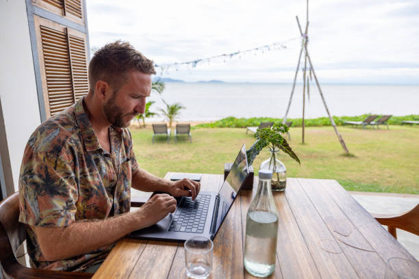 istock Freelancer working on laptop at tropical beachside 2191769833