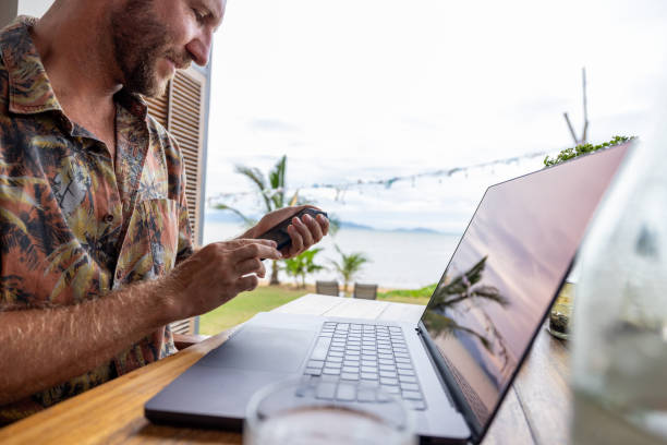 istock Man in Tropical Location Working on Laptop with Phone 2191769834