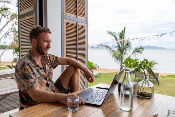istock Man Working on Laptop in Tropical Cafe 2191769896
