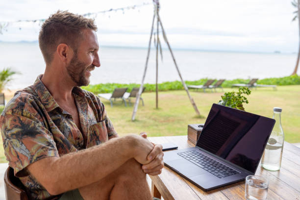 istock Man Working on Laptop at Tropical Beachfront Cafe 2191770001
