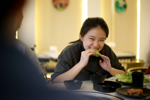 An Asian teenage girl is enjoying Mookata (Thai Hotpot and Barbeque) in restaurant