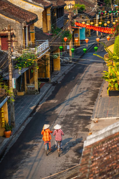 Vietnamese women ride bikes in an old town of Hoi An city, Vietnam stock photo