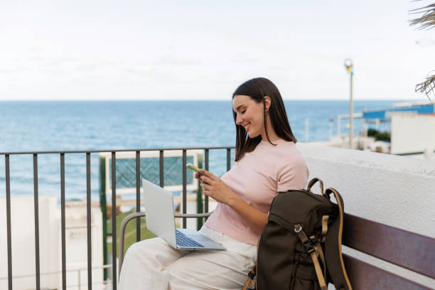 istock Young woman working remotely using laptop and smartphone while enjoying the seaside view, embracing the digital nomad lifestyle 2191782818