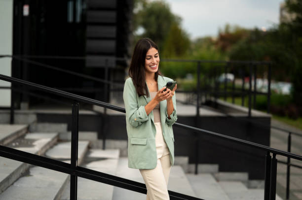 istock Young female going down the steps and using her smart phone for talking and online message 2191786055