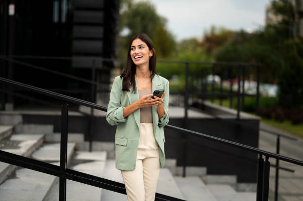 istock Young female going down the steps and using her smart phone for talking and online message 2191786060